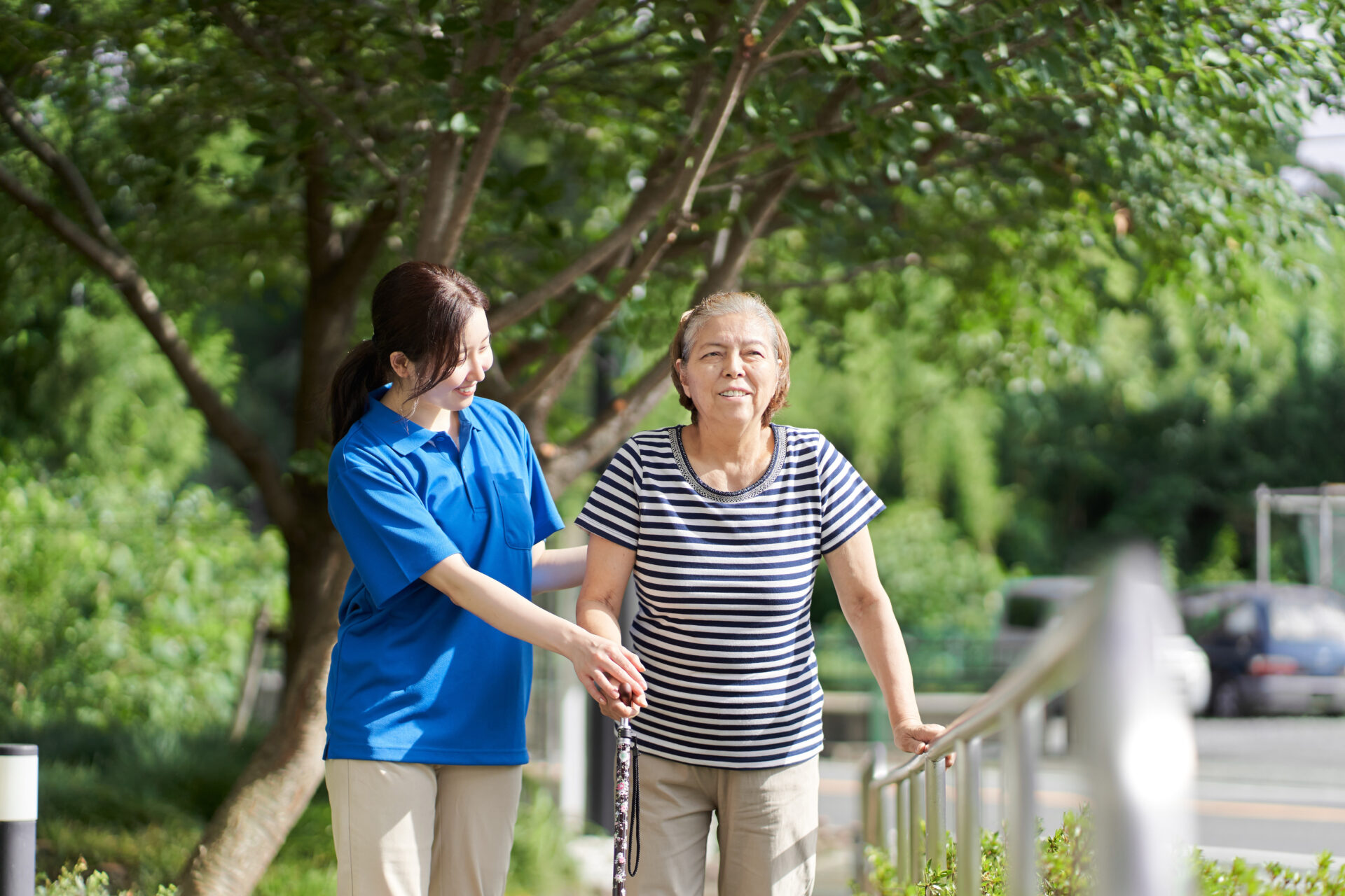 女性介護士の介助で歩く高齢者